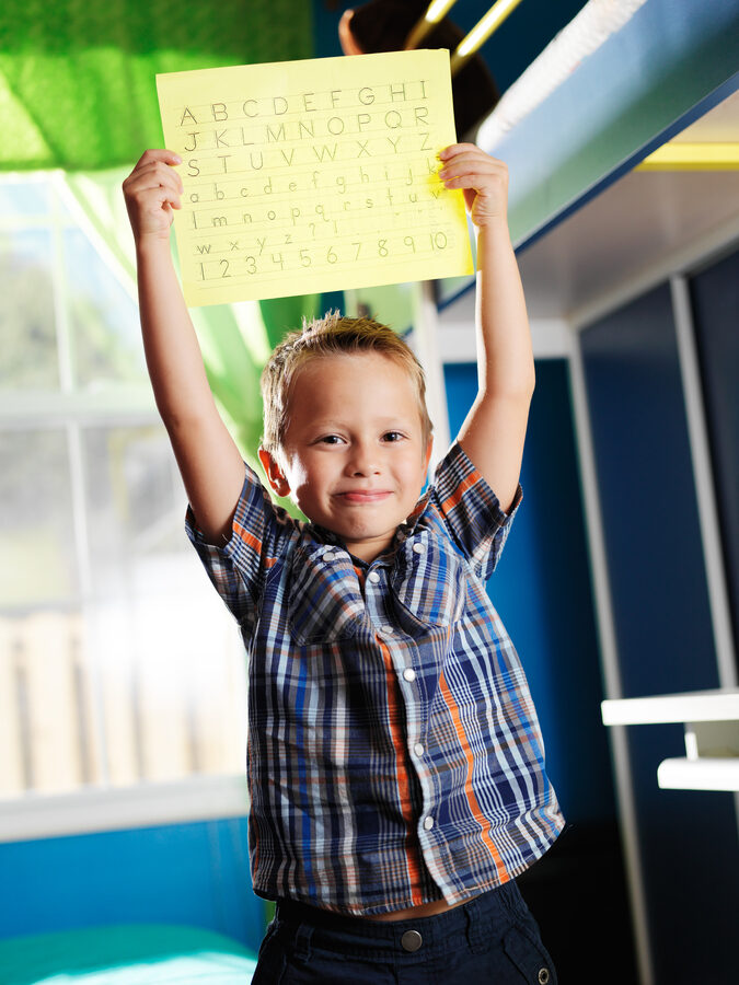 cute little boy showing his alphabet worksheet