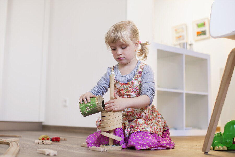 Girl kneeling on wooden floor playing with toys