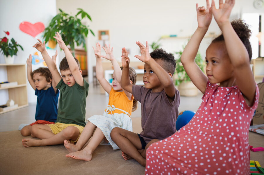 Group of small nursery school children sitting on floor indoors in classroom, playing.
